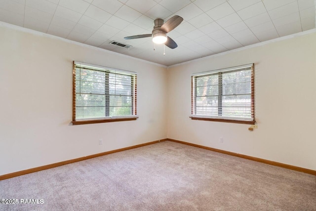 carpeted empty room with crown molding, ceiling fan, and a wealth of natural light