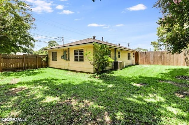 rear view of house featuring central AC unit and a yard