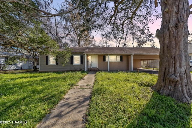 ranch-style house featuring a carport and a yard