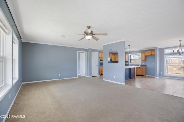 unfurnished living room featuring light carpet, ceiling fan with notable chandelier, baseboards, and crown molding