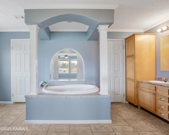 bathroom with a relaxing tiled tub, tile patterned floors, decorative columns, and vanity