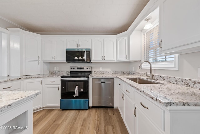 kitchen with sink, light wood-type flooring, appliances with stainless steel finishes, light stone countertops, and white cabinets