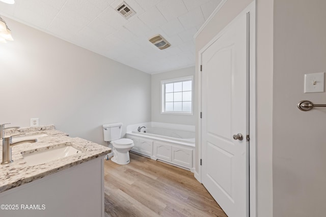 bathroom with wood-type flooring, a tub, vanity, and toilet