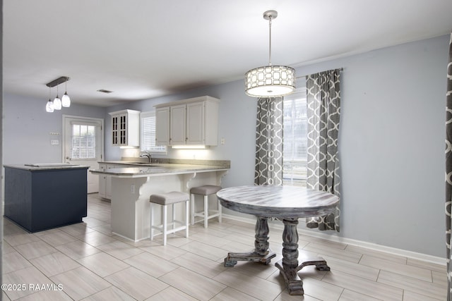 kitchen with white cabinetry, decorative light fixtures, a breakfast bar area, and kitchen peninsula