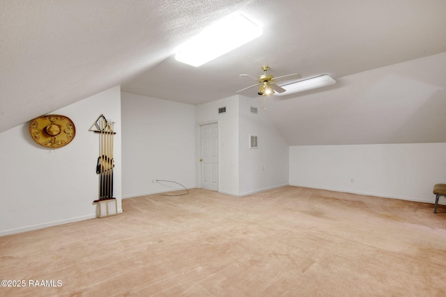 additional living space with lofted ceiling, ceiling fan, light colored carpet, and a textured ceiling