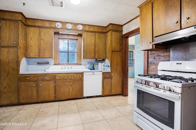 kitchen with light tile patterned flooring, sink, crown molding, and white appliances