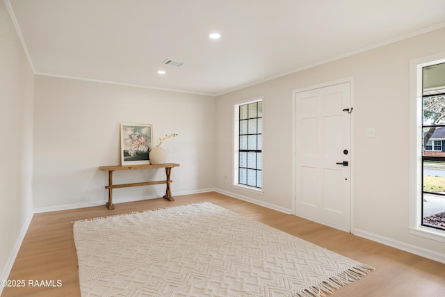 foyer featuring ornamental molding, light hardwood / wood-style flooring, and a wealth of natural light