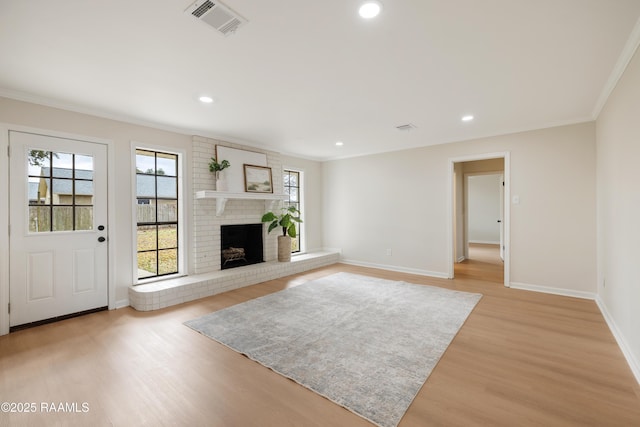 unfurnished living room with ornamental molding, plenty of natural light, a fireplace, and light hardwood / wood-style flooring