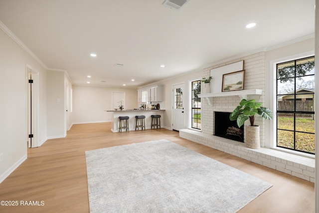 unfurnished living room with ornamental molding, a brick fireplace, and a wealth of natural light