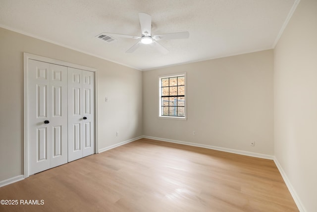 unfurnished bedroom with crown molding, a textured ceiling, a closet, and light wood-type flooring