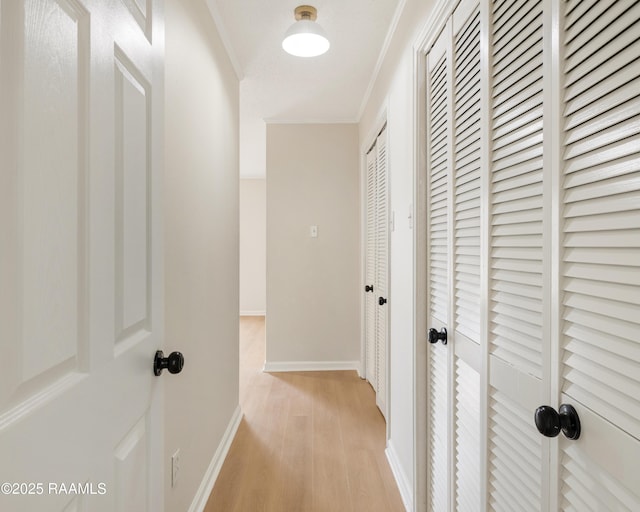 corridor with ornamental molding and light hardwood / wood-style flooring