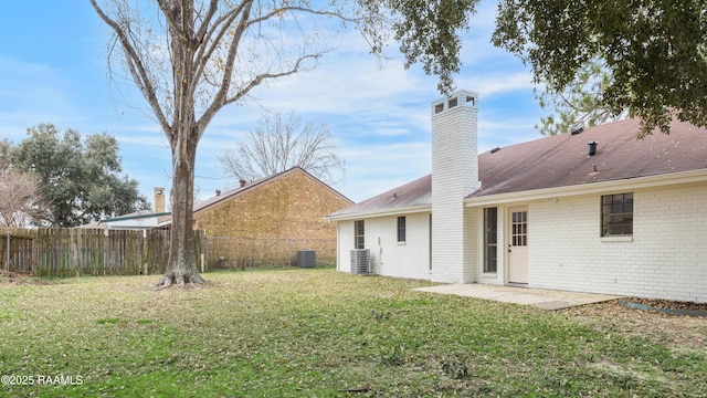 rear view of house featuring cooling unit, a patio, and a lawn