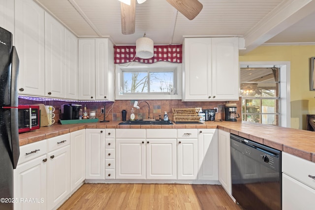 kitchen featuring a sink, light wood-style flooring, tile countertops, white cabinetry, and black appliances