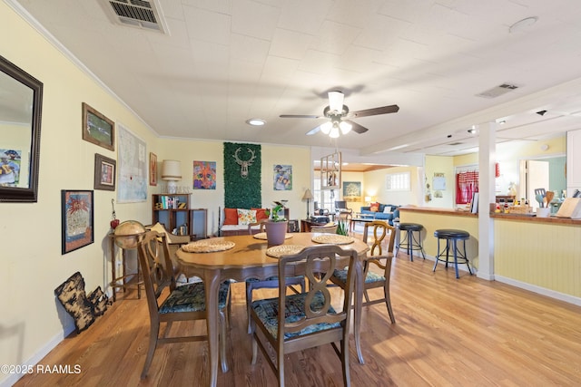 dining space featuring ceiling fan, ornamental molding, visible vents, and light wood-style floors