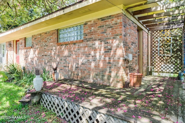 view of property exterior featuring brick siding and a deck