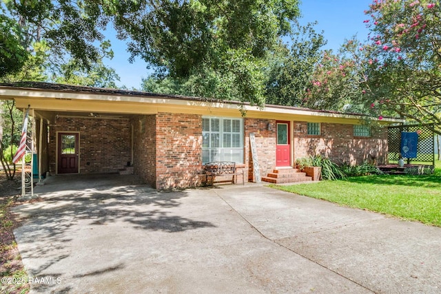 single story home with entry steps, concrete driveway, a front yard, a carport, and brick siding