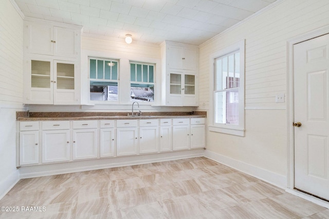 kitchen with white cabinetry, sink, and ornamental molding