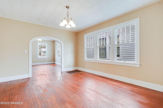 empty room featuring hardwood / wood-style floors, a notable chandelier, and ornamental molding