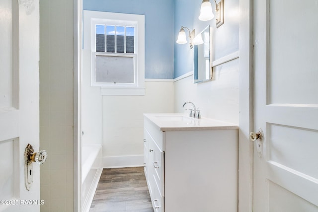 bathroom with hardwood / wood-style flooring, a tub to relax in, and vanity