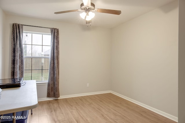 spare room featuring a ceiling fan, baseboards, and light wood finished floors