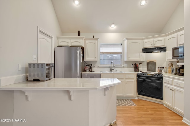 kitchen with lofted ceiling, stainless steel appliances, a breakfast bar, a peninsula, and a sink