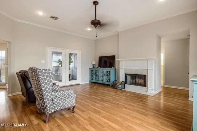 living area featuring a wealth of natural light, visible vents, a tiled fireplace, and wood finished floors