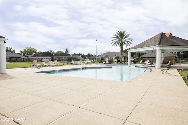 community pool featuring fence, a gazebo, and a patio