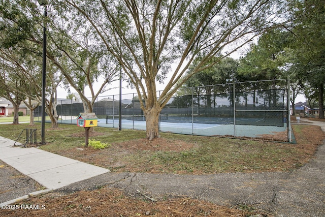 view of property's community with a tennis court and fence