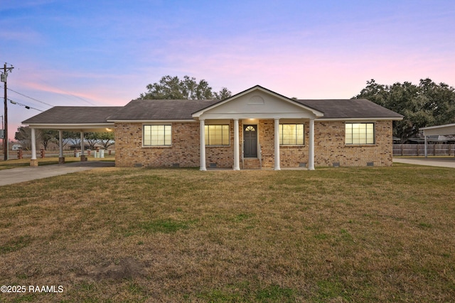 ranch-style house featuring a carport and a lawn