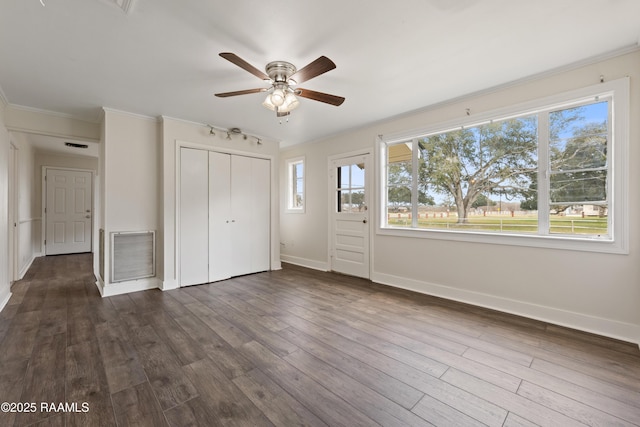 unfurnished bedroom with multiple windows, dark wood-type flooring, ornamental molding, and a closet