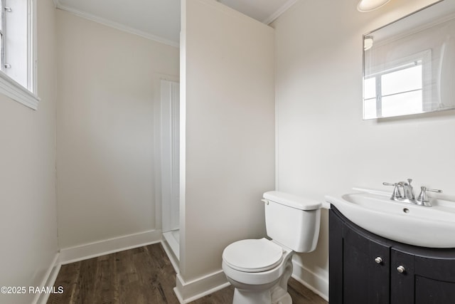 bathroom with toilet, a shower, ornamental molding, vanity, and hardwood / wood-style floors