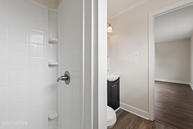 bathroom with hardwood / wood-style floors, a tile shower, vanity, ornamental molding, and toilet