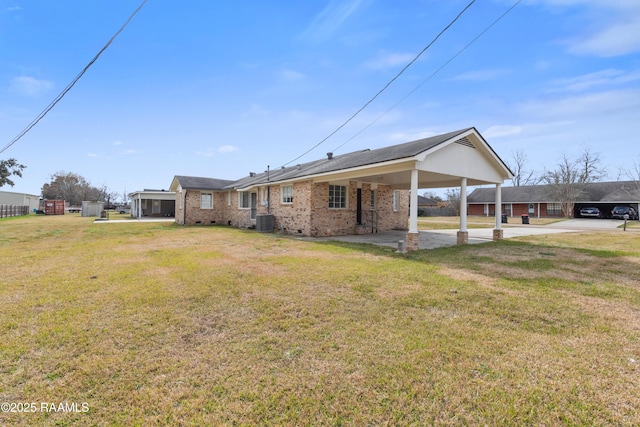 rear view of house with cooling unit, a yard, and a carport