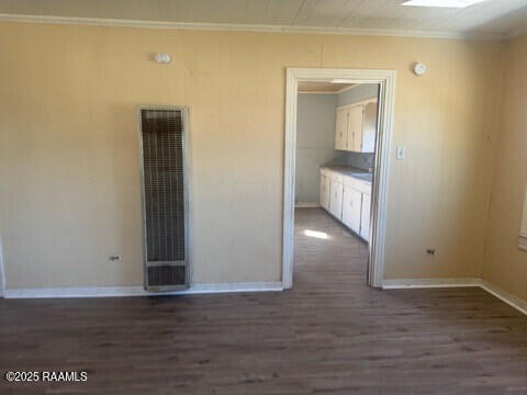 empty room featuring ornamental molding and dark wood-type flooring