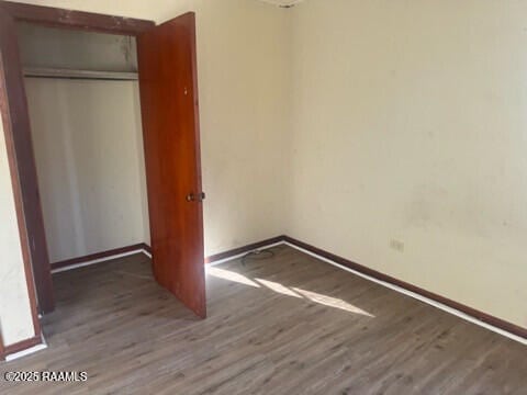 unfurnished bedroom with dark hardwood / wood-style flooring and a closet