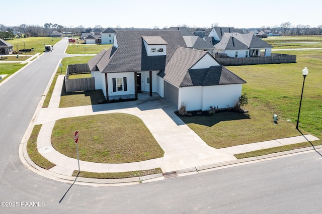 view of front facade featuring fence, a residential view, a front lawn, and driveway