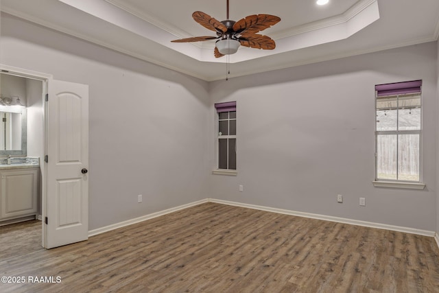 spare room with ornamental molding, a tray ceiling, and hardwood / wood-style floors