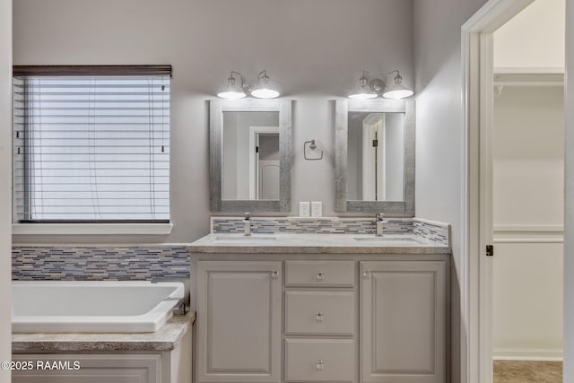 bathroom with vanity, a washtub, and backsplash