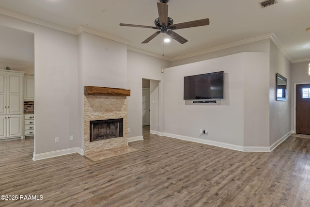 unfurnished living room with crown molding, ceiling fan, a stone fireplace, and light hardwood / wood-style flooring