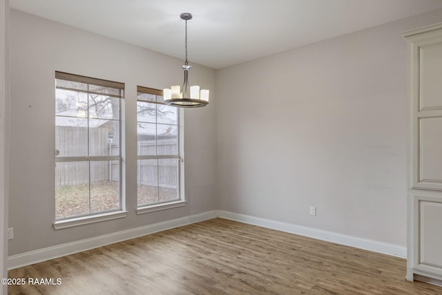 empty room featuring an inviting chandelier and wood-type flooring