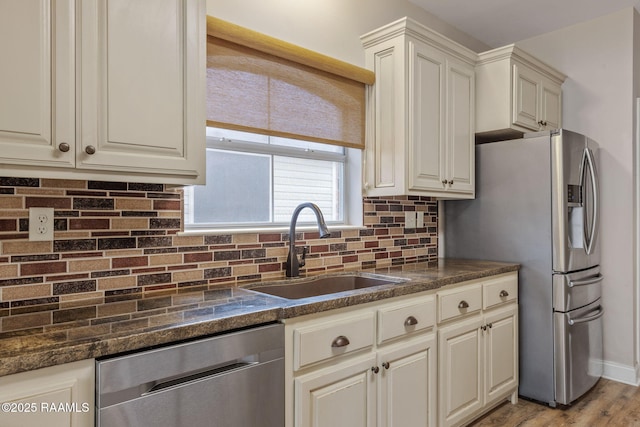 kitchen featuring sink, tasteful backsplash, light hardwood / wood-style flooring, appliances with stainless steel finishes, and cream cabinets