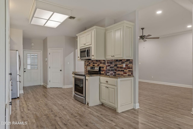 kitchen with appliances with stainless steel finishes, backsplash, ceiling fan, light hardwood / wood-style floors, and cream cabinets