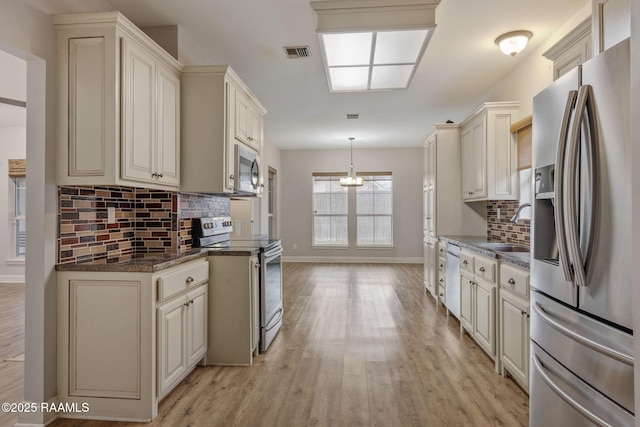 kitchen featuring sink, hanging light fixtures, light hardwood / wood-style flooring, stainless steel appliances, and cream cabinetry