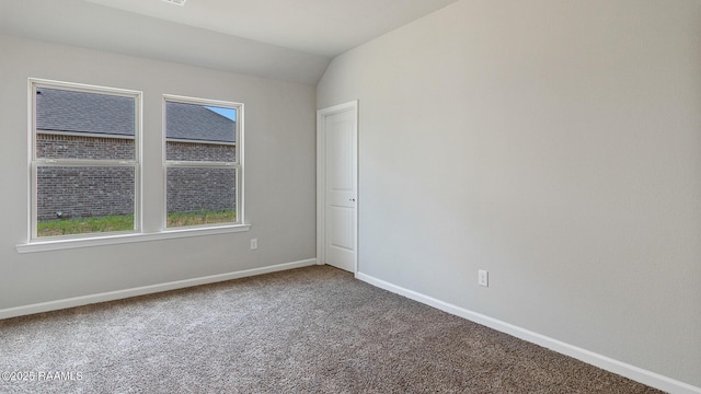 carpeted empty room with vaulted ceiling