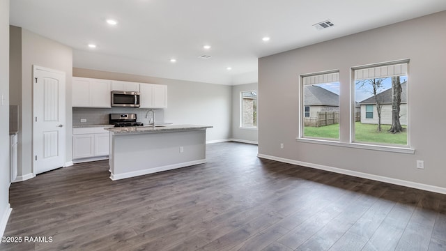 kitchen featuring tasteful backsplash, a center island with sink, appliances with stainless steel finishes, dark hardwood / wood-style floors, and white cabinets