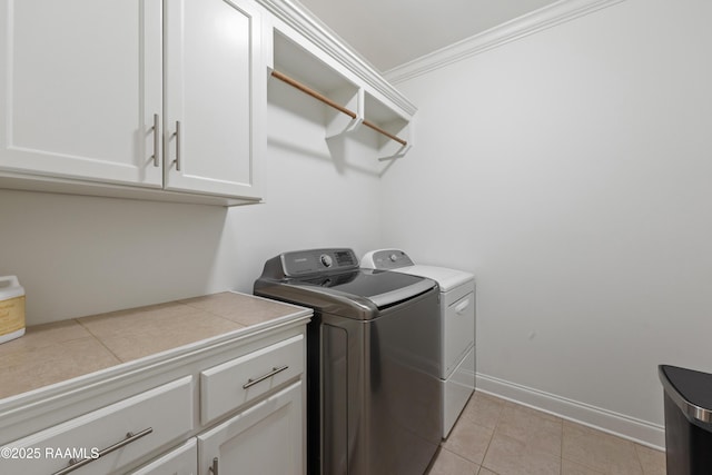 laundry room with light tile patterned floors, crown molding, washer and clothes dryer, and cabinets