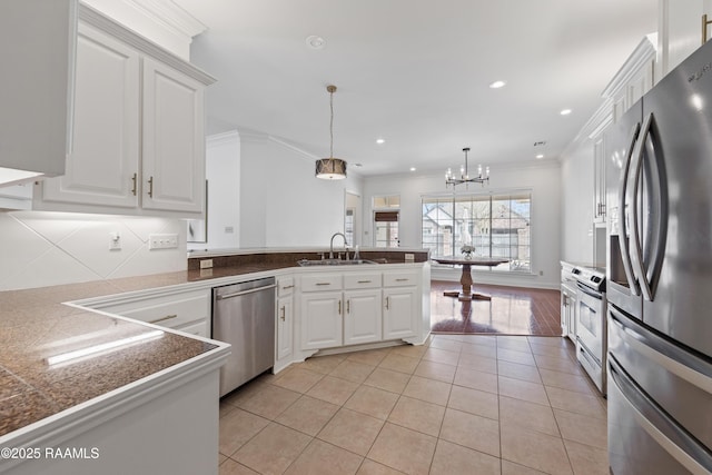 kitchen with appliances with stainless steel finishes, decorative light fixtures, white cabinets, light tile patterned floors, and kitchen peninsula