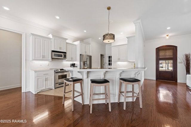 kitchen with pendant lighting, appliances with stainless steel finishes, decorative backsplash, and white cabinets