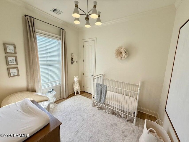 bedroom with hardwood / wood-style flooring, ornamental molding, and an inviting chandelier