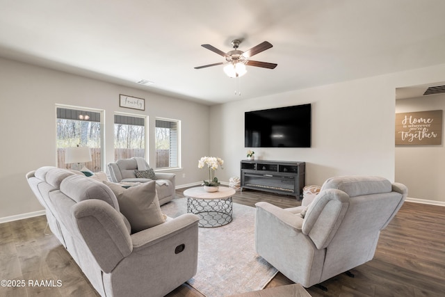 living area featuring a ceiling fan, wood finished floors, visible vents, and baseboards